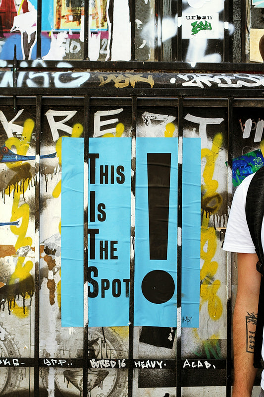 A wooden fence painted with the words This Is The Spot!