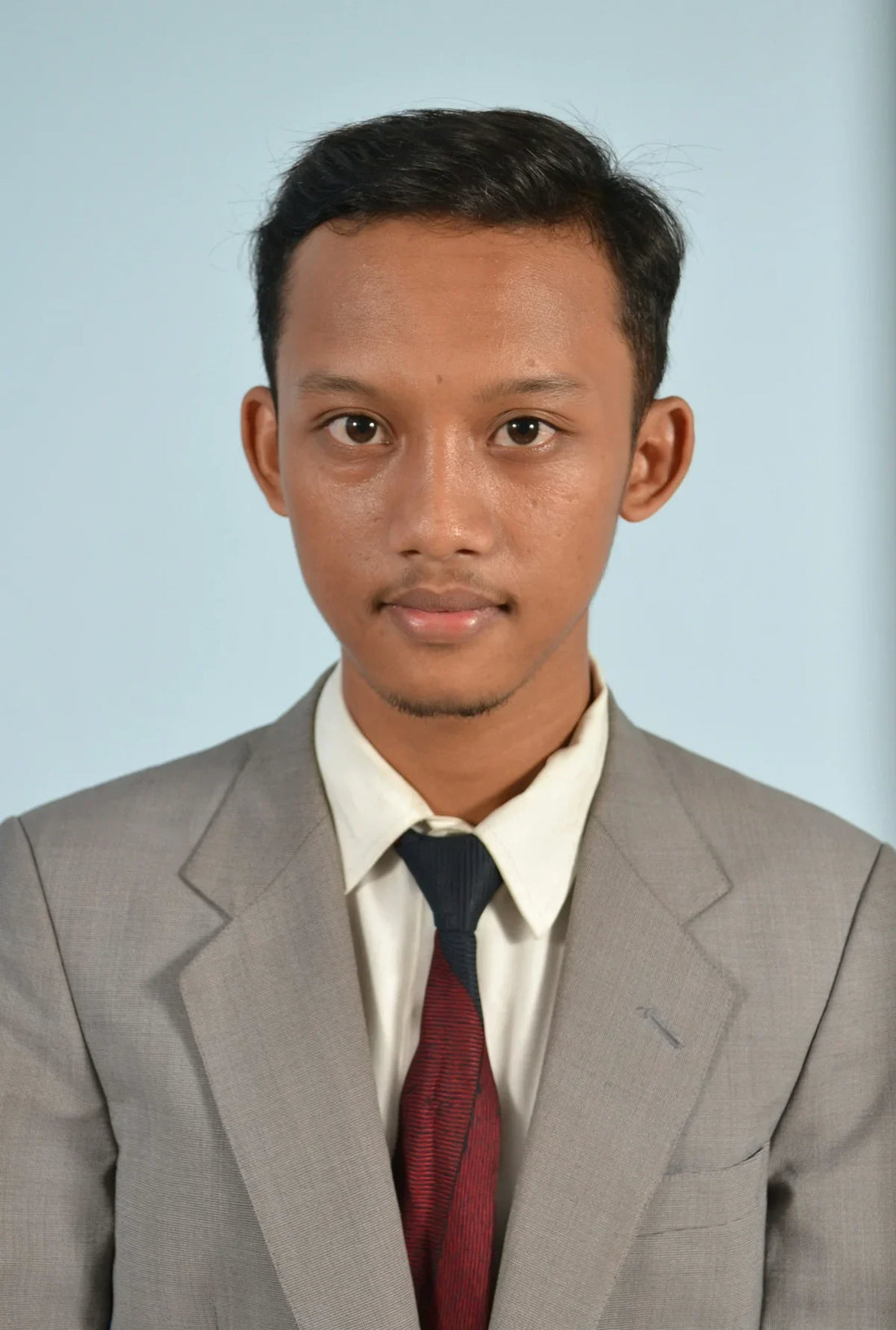 A young man in a formal suit poses for a portrait showcasing the best grill for camping and yachting
