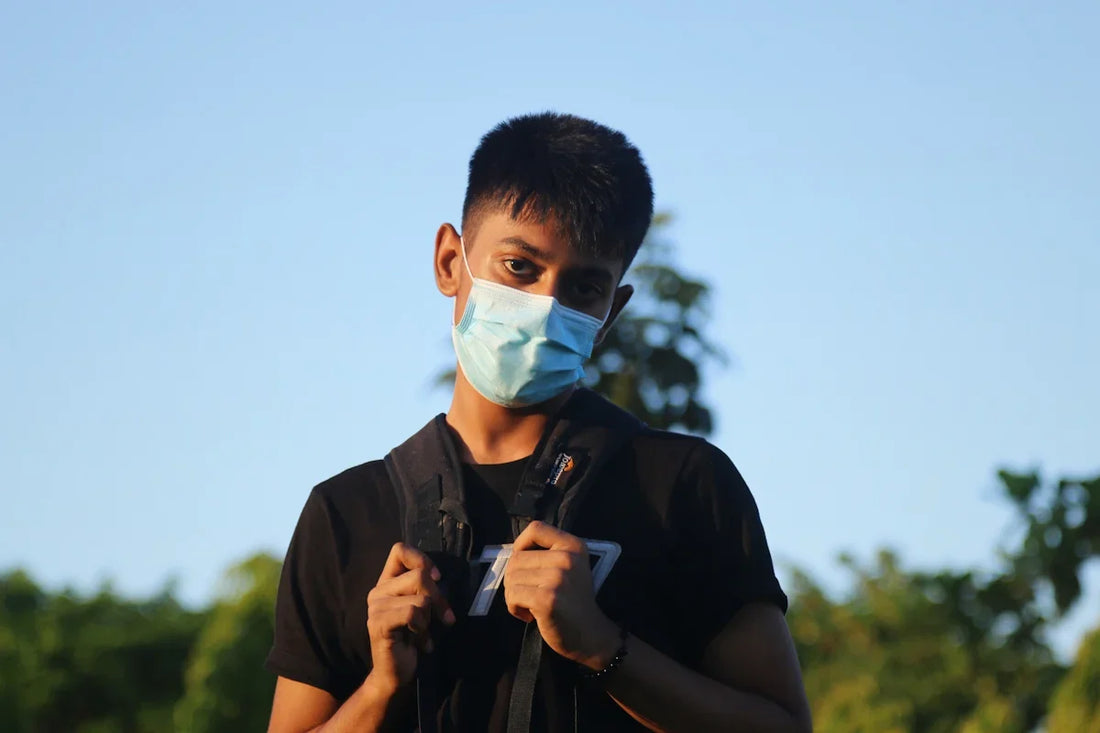 A man wears a mask outside on a sunny day.