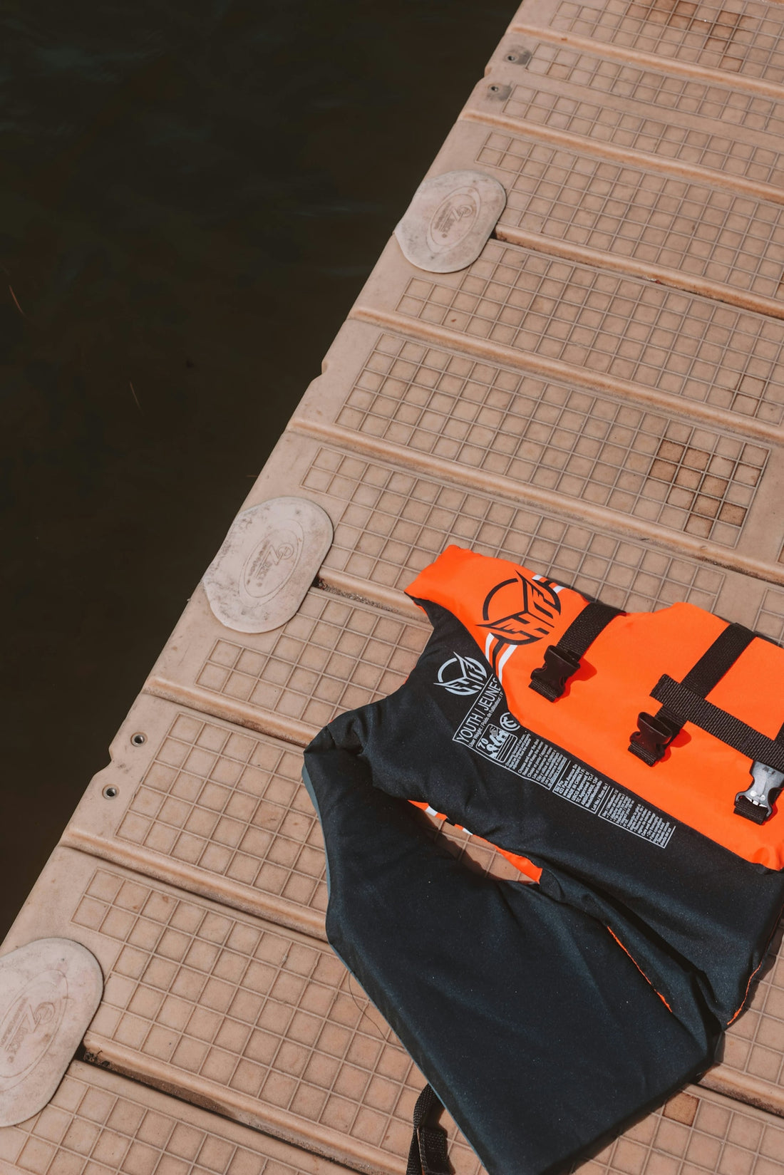 Life jackets rest on a dock near the water.
