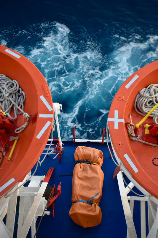 Two orange lifeboats on a ship deck over blue water.