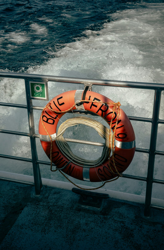 Orange life preserver hanging on a boat railing.