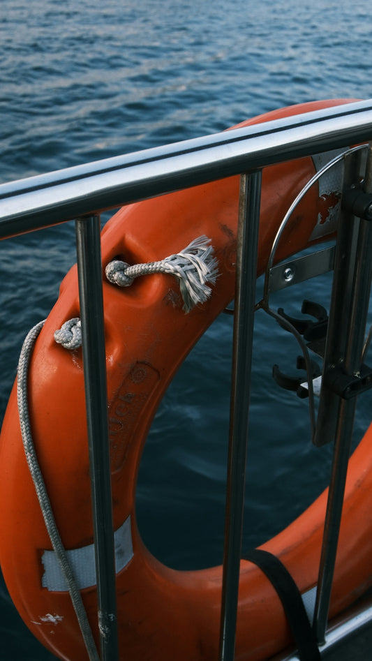 Orange life preserver attached to boat railing over water