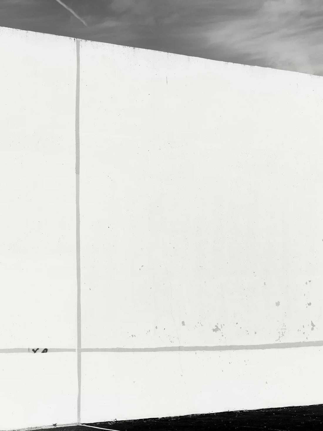 A stark white wall with subtle lines against sky