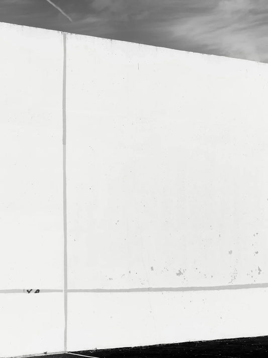 A stark white wall with subtle lines against sky