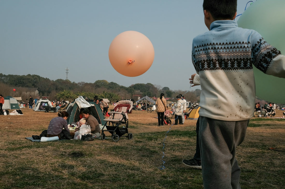 A boy holds a balloon at an outdoor gathering.