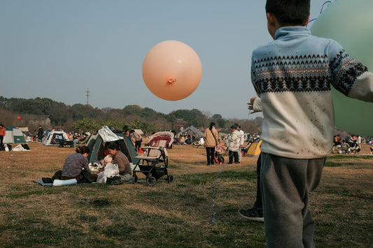 A boy holds a balloon at an outdoor gathering.