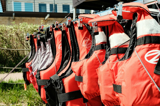 Multiple orange life jackets hanging in a row.