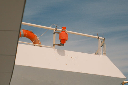 An orange lifebuoy and safety device on a white boat.
